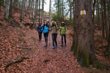 Yağmurlu bir günde dağlarda sırt çantalı kadınlar yürüyüş yapıyor.