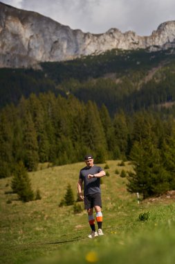 Bir çayırda dağlarla koşan bir yarışçı.