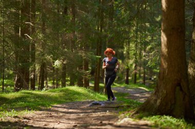 Kızıl saçlı kadın, ormanda koşucu eğitimi alıyor.