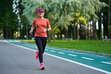 Atletik bayan koşucu parkta koşuyor. 