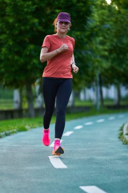 Atletik bayan koşucu parkta koşuyor. 
