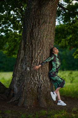 Yüzüncü yıl ağaçlarıyla ormanda yeşil elbiseli İspanyol genç manken.