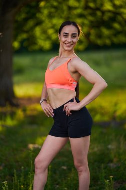 Formanın yanındaki çayırda çeşitli pozlarda poz veren spor modeli.