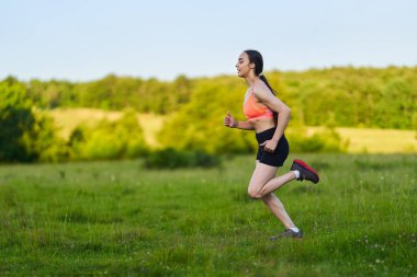 Genç fitness kızı ormanda koşuyor.