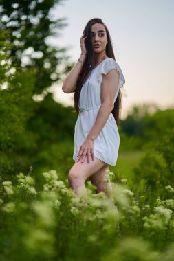 Ormanın yanındaki çiçek tarlasında beyaz elbiseli güzel bir İspanyol kadın.