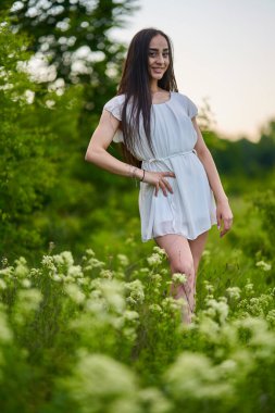 Ormanın yanındaki çiçek tarlasında beyaz elbiseli güzel bir İspanyol kadın.