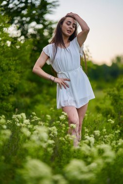 Ormanın yanındaki çiçek tarlasında beyaz elbiseli güzel bir İspanyol kadın.