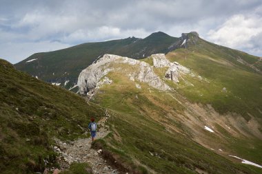 Yazın Alp dağlarında sırt çantalı kızıl saçlı kadın yürüyüşçü.