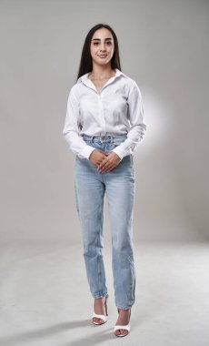 Mutlu İspanyol iş kadınının gri arka planda tam boy stüdyo portresi