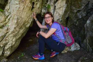 Sırt çantalı bir kadın güneşli bir yaz gününde dağlarda yürüyüş yapıyor.