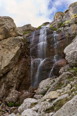 Akşamları yüksek dağlarda şelalesi olan canlı bir manzara.