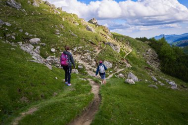 Yaz tatili boyunca dağlarda yürüyüş yapan sırt çantalı iki kadın yürüyüşçü.