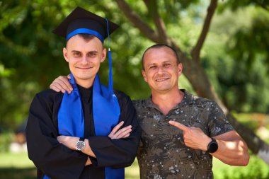 Genç adam üniversite mezunu ve babası, dışarıda poz veriyor ve eğleniyor.