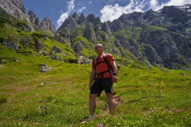 Sırt çantalı atletik bir adam yaz günü yüksek dağlarda yürüyüş yapıyor.