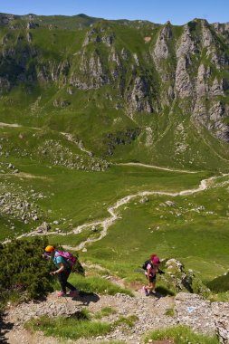 Yaz dağlarında sırt çantalı iki yürüyüşçü.