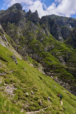 Sırt çantalı iki kadın dağlarda yürüyüş yapıyor.