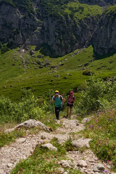 Sırt çantalı ve sırıkla dağlarda yürüyüş yapan iki kadın.