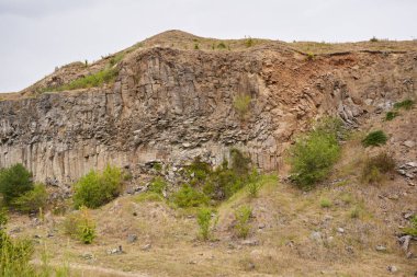 Taş ocağındaki kaya oluşumlarının, bazalt ve dross katmanlarının yaz manzarası