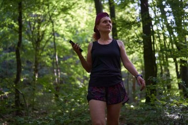 Yazın sonlarında yaprak döken ormanda yürüyüş yapan bir kadın.