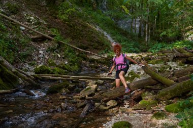 Yaz sonlarında dağlarda nehri geçen bir kadın yürüyüşçü.