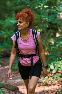 Kızıl saçlı yürüyüşçü dağlarda gündüz vakti ormanda