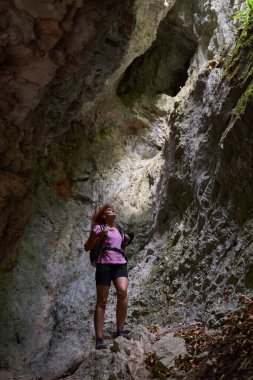 Sırt çantalı bir kadın kireçtaşı dağlarında çatısında bir delik olan mağarayı keşfediyor.