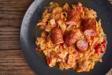 Fırında lahana güveci, domuz jambonu ve ahşap bir tahtanın üzerinde sosis.  