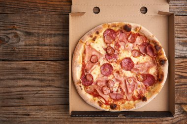 Kopya uzayı olan ahşap bir tahtanın üzerindeki mukavva içinde pizza.