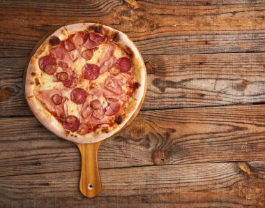 Fırından yeni çıkmış bir pizzanın düz görüntüsü. Köy tahtasının üzerinde kopyasal alan var.