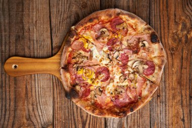 Fırından yeni çıkmış bir pizzanın düz görüntüsü. Köy tahtasının üzerinde kopyasal alan var.