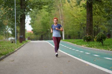 Atletik kadın koşucu sabah saatlerinde parkta koşuyor. 