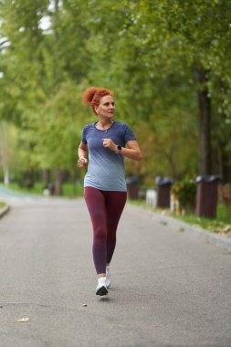 Atletik kadın koşucu sabah saatlerinde parkta koşuyor. 