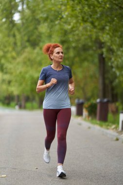 Atletik kadın koşucu sabah saatlerinde parkta koşuyor. 