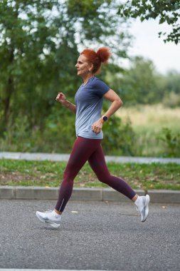 Sonbaharın başında parkta koşan olgun bir kadın