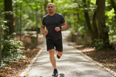 Atletik adam sabah parkta koşuyor. 