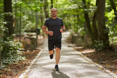 Atletik adam sabah parkta koşuyor. 