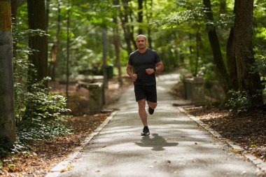 Atletik adam sabah parkta koşuyor. 