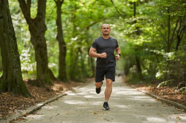 Erkek koşucu sabah geç saatlerde yaz parkında koşuyor