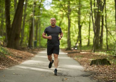 Sabahları güz parkında koşan atletik bir adamın gündüz görüşü 
