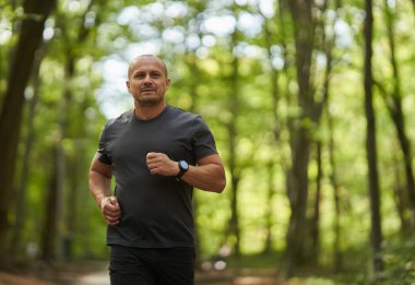 Sabahları güz parkında koşan atletik bir adamın gündüz görüşü 