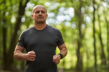 Sabahları güz parkında koşan atletik bir adamın gündüz görüşü 