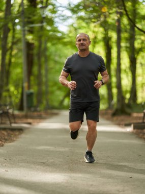 Sabahları güz parkında koşan atletik bir adamın gündüz görüşü 