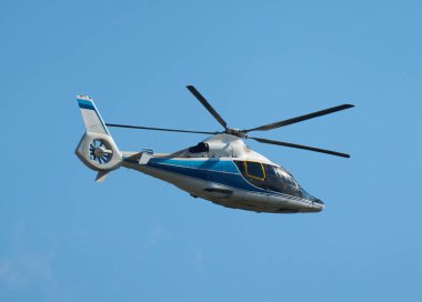 Mavi-beyaz bir helikopterin açık gökyüzüne doğru hareketli görüntüsünü durdur.