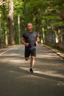Sonbaharın başlarında sabah parkta koşu yaparken aktif bir adam.