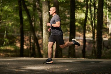 Sonbaharın başlarında sabah parkta koşu yaparken aktif bir adam.