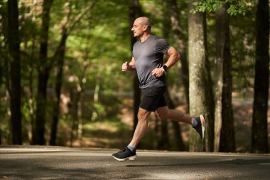 Atletik adam yazın sonlarında sabah parkta koşar.