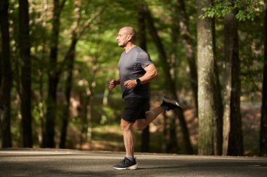 Atletik erkek koşucu yazın sonlarında sabah parkta.