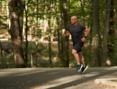 Sonbaharın başlarında sabah parkta koşu yaparken aktif bir adam.