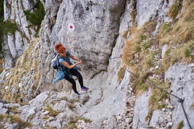 Ferrata 'yla dik bir patikaya tırmanan kadın.