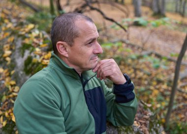 50 'li yaşlarda bir adamın portresi, ormanda yüz ifadeleri sergiliyor. 